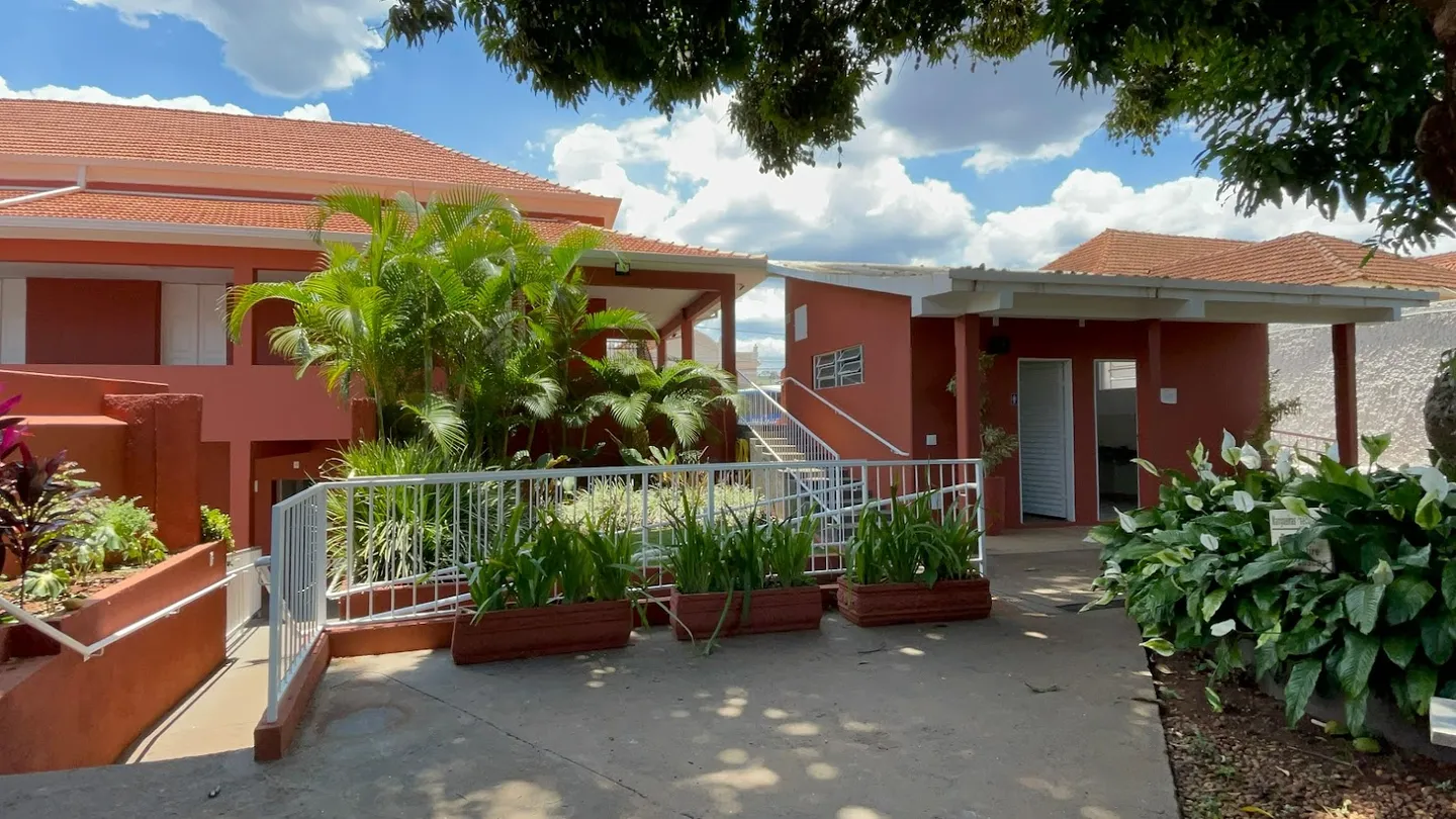 Pátio interno do Colégio Allan Kardec, com corredor coberto e pérgola florida