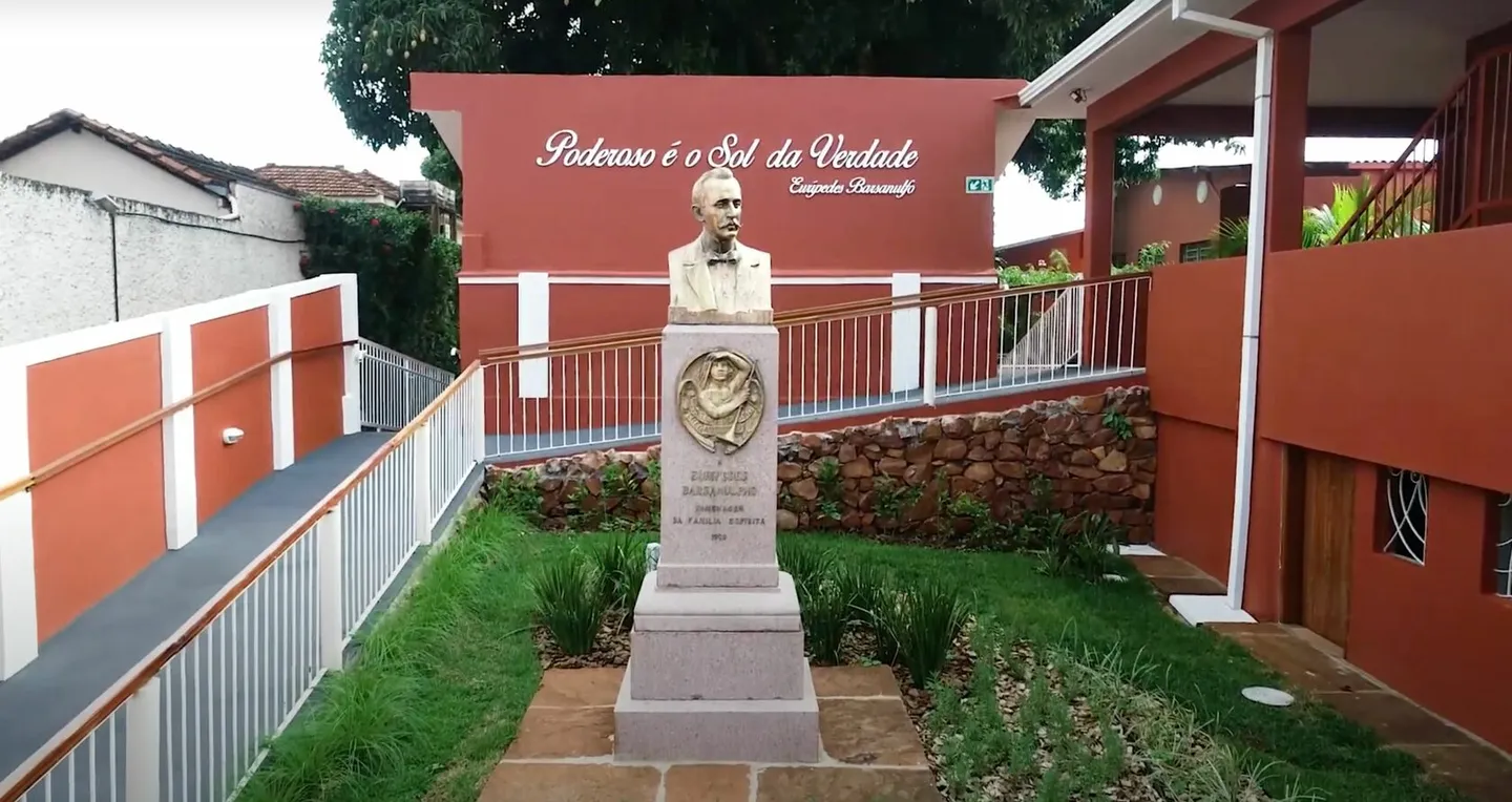 Busto de Eurípedes Barsanulfo no jardim, diante do muro com a frase Poderoso é o Sol da Verdade
