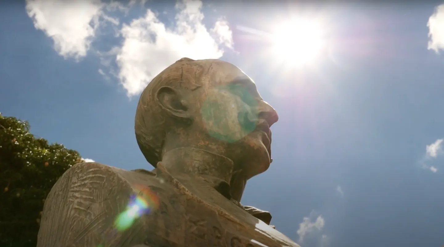 Busto de Eurípedes Barsanulfo contra o céu, com o sol ao fundo