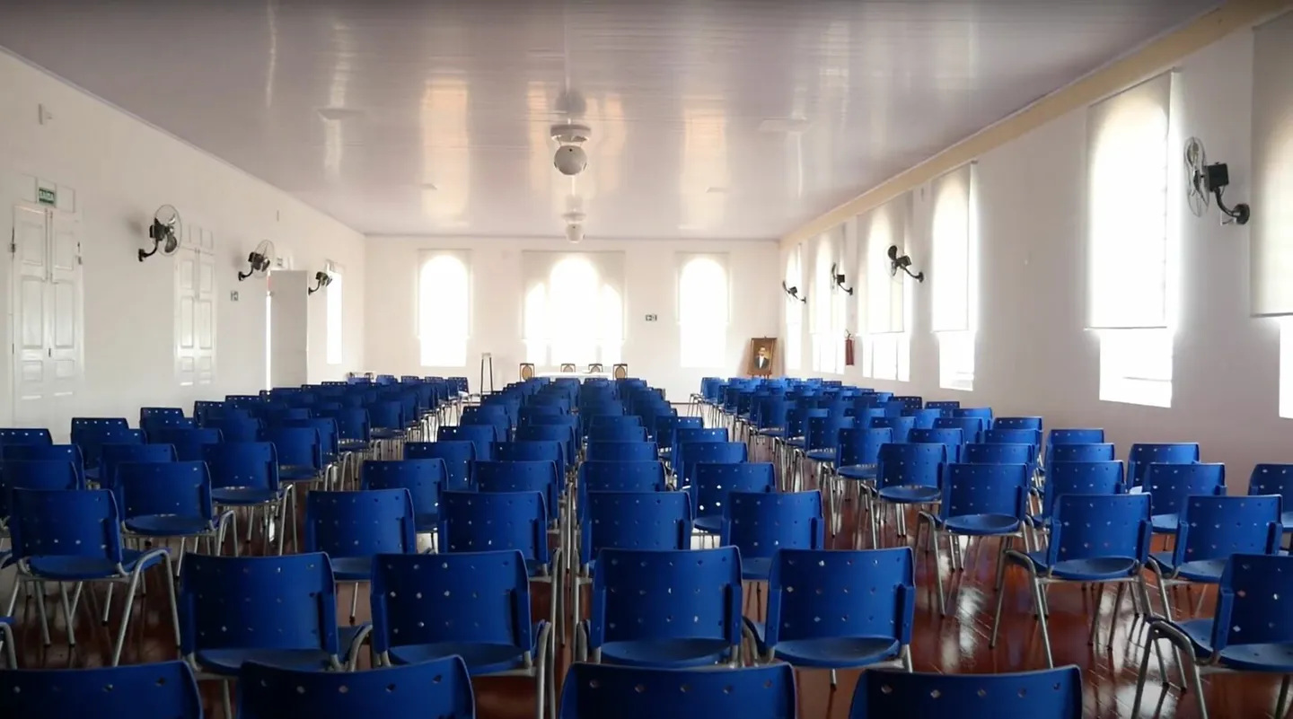 Salão interno com fileiras de cadeiras azuis